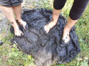 Zdjęcie przedstawia stopy dwóch osób stojących w błocie.